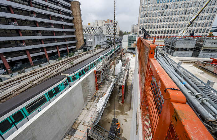 Les compagnons construisent les murs du bâtiment voyageurs le long des voies de la ligne 8 du métro.