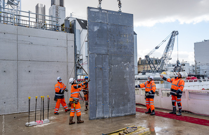 Pendant que sous terre le creusement de l’espace intérieur de la gare se termine, les compagnons débutent en surface la construction du bâtiment voyageurs.