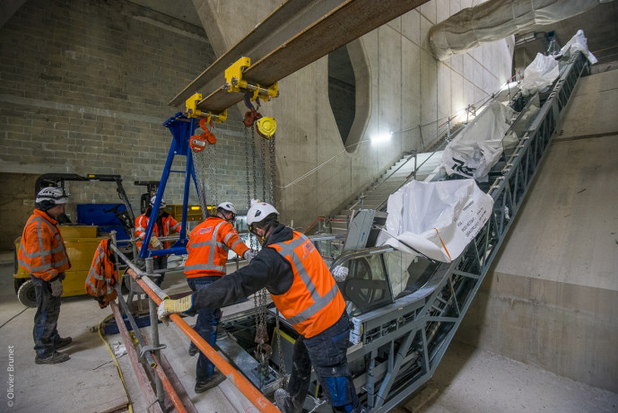 Après avoir assemblé les pièces de l’escalier mécanique, les compagnons le fixent et installent le mécanisme. 